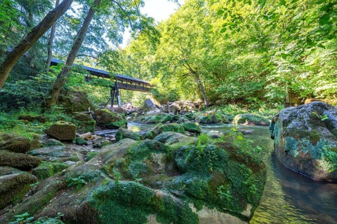 The Irrel Waterfalls, rapids in the lower reaches of the Prüm, covered wooden bridge for hikers,