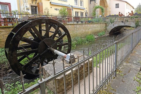 Waterwheel at the stream casting with metal fence, idyll, Meisenheim, Rhineland-Palatinate,