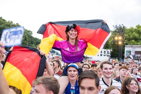 Celinda celebrates with a German flag on her boyfriend's shoulders in the fan zone at the