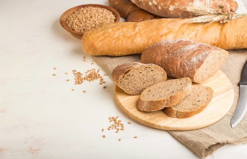 Sliced bread with different kinds of fresh baked bread on a white wooden background. side view,