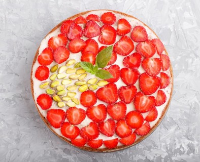 Homemade cake with yoghurt cream, strawberry and pistachio on a gray concrete background. top view.