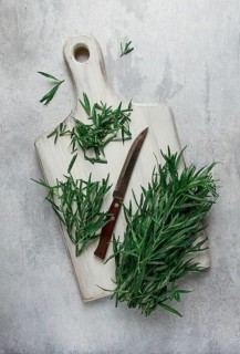 Fresh Tarragon, on a cutting board, slicing, on a light table, top view, no people
