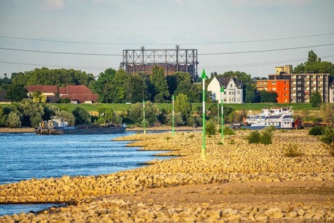 Cargo ship at low water on the Rhine near Duisburg-Homberg, view of Duisburg-Laar, houses on