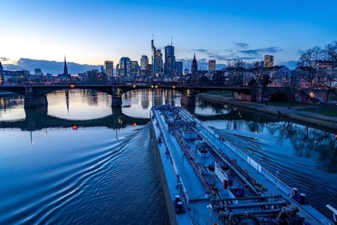 Skyline of the city centre of Frankfurt am Main, river Main, dusk, Ignatz-Bubis-Bridge, cargo ship,