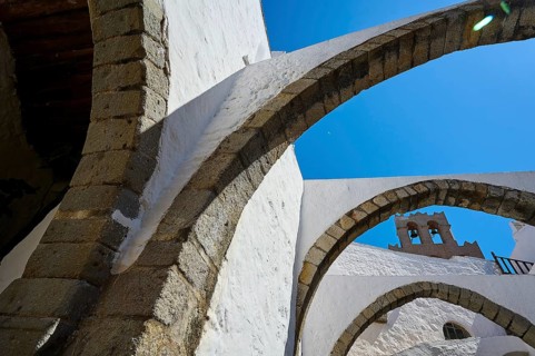 Stone arch and bell tower on a sunny day, Part of a medieval monastery with white walls, Inside the