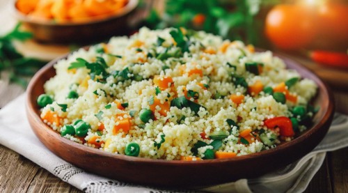 A bowl of couscous with a variety of vegetables and grains, AI generated