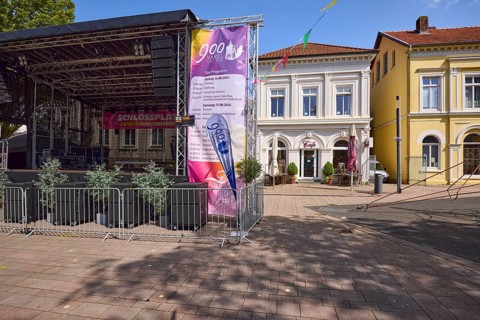 Stage with programme for the 900th anniversary celebrations and pastel-coloured houses with pointed