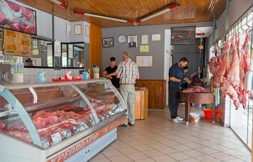 Customers and butchers in a butcher's shop full of meat products and a busy atmosphere, Gastouni,