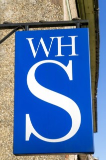 Close up of WH Smith brand logo sign mounted on wall, Hungerford, Berkshire, UK