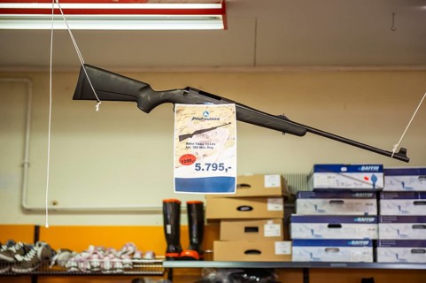 Hunting rifle hanging in supermarket with price tag, Inuit settlement Ittoqqortoormiit,