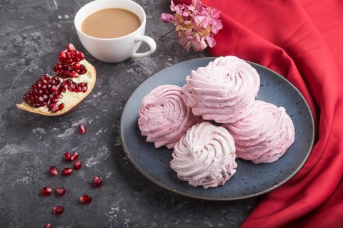 Pink pomegranate homemade zephyr or marshmallow with cup of coffee on a black concrete background