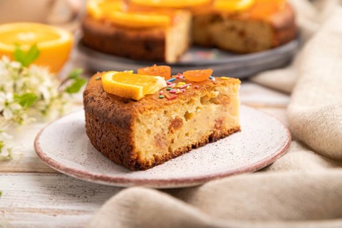 Orange cake and a cup of coffee on a white wooden background and linen textile. Side view, close