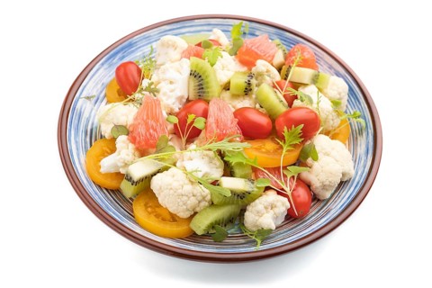 Vegetarian salad of cauliflower cabbage, kiwi, tomatoes, microgreen sprouts isolated on white