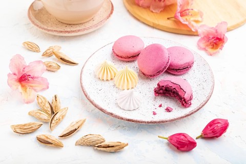 Purple macarons or macaroons cakes with cup of coffee on a white concrete background decorated with