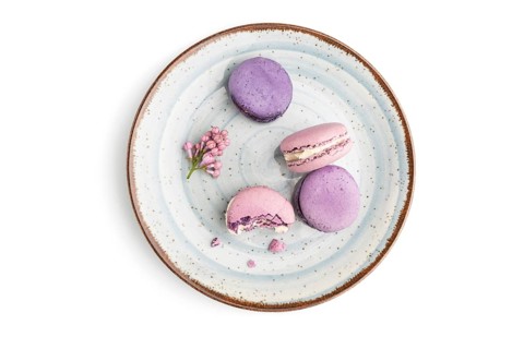Purple macarons or macaroons cakes on blue plate isolated on white background. Top view, flat lay,