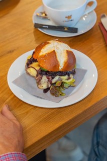 A burger on a pretzel bun with a napkin on a plate, autumn creations, Cafe Kuh, Deckenpfronn, Black