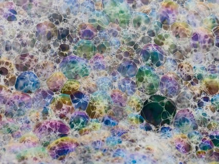 Colorful patterns of bubbles on the beach, caused by the wind blowing the sea spray inland, where