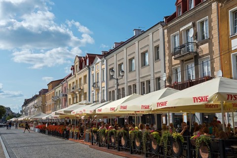 Lively street scene with restaurants and parasols in a historic old town centre in sunny weather,