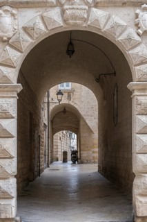 Narrow corridor with arches and stone walls, illuminated by ancient lanterns in a historic