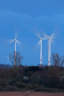 Luminous wind turbines rotating in an area surrounded by trees in the evening light, Wind turbines