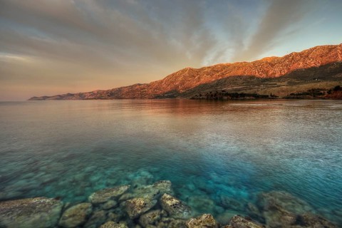 Morning light falls on a rocky coast with clear sea water, Mani peninsula, Peloponnese, Greece,