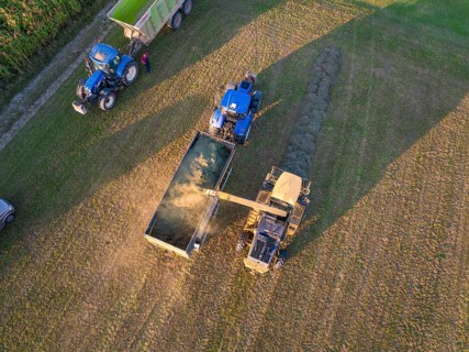 Aerial view of two tractors and a trailer working in a field during the harvest, Haselstaller Hof,