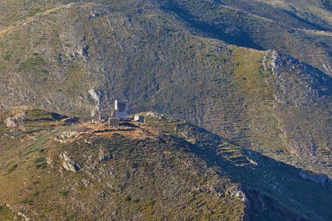 An old ruined tower on a hilly mountain with green vegetation on a sunny day, Mani Peninsula,