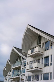 A modern residential building with several balconies and glass fronts under a cloudy sky, Molde,