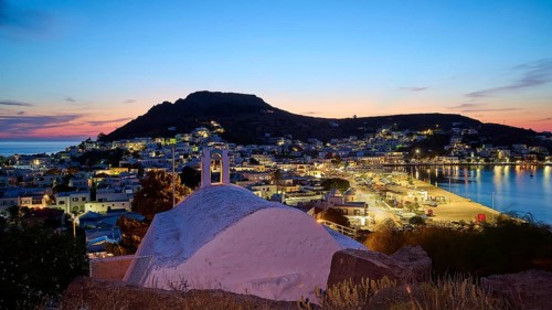Agia Paraskevi Chapel, Illuminated coastal town at night with a view of the sea and hills in the