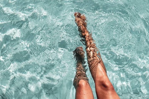 Legs in turquoise-coloured pool water, summery and peaceful scene