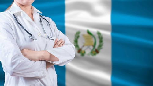Healthcare concept with Guatemalan flag in background. Doctor with arms crossed with Guatemala flag
