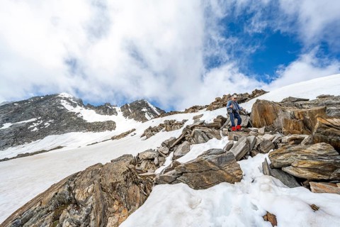 Mountaineer on a hiking trail between snow, descent from the summit of Schönbichler Horn, view of