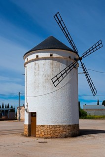Small white windmill with blades and stone base under a clear sky, Mill, Molino de Villahermosa, La