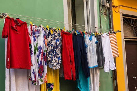 Men's and women's washed clothes drying on clothesline of green painted with white trim stucco