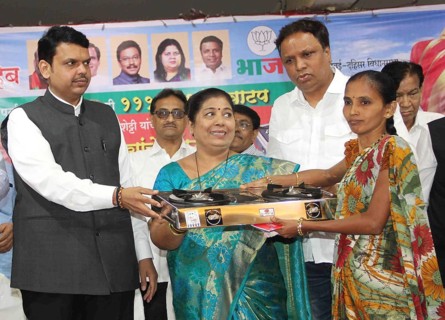 Maharashtra Chief Minister Devendra Fadnavis (L) distributes gas stoves to underpriviledged women