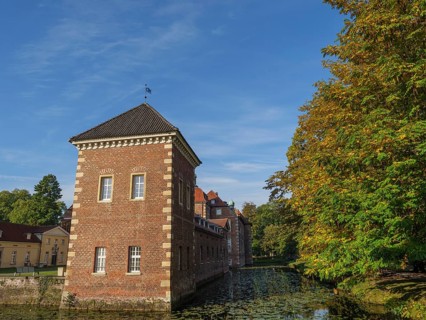 Historic brick building next to a river and autumn-coloured trees, velen, westphalia, germany