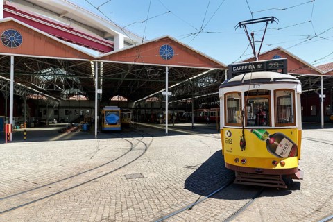 Historic yellow tram, Eléctrico, line 28 in front of tram depot and repair shop, Lisbon, Portugal,