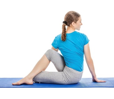 Yoga, young beautiful slender woman yoga instructor doing Half Lord of the Fishes Pose (Half Spinal