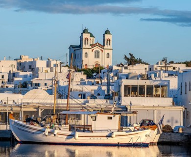 Fishing boats in the harbour at sunset, reflected in the sea, White Cycladic houses and church