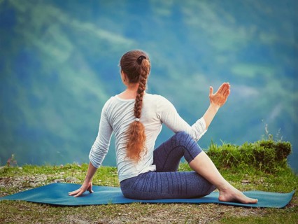 Hatha yoga outdoors, sporty fit woman doing yoga asana Parivrtta Marichyasana (or ardha