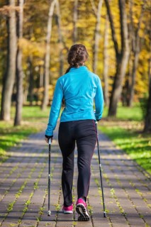 Nordic walking adventure and exercising concept, woman hiking withnordic walking poles in park