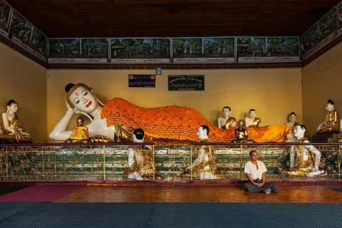 YANGON, MYANMAR, JANUARY 3, 2014: Man meditating near statue of Recumbent Buddha in Shwedagon Paya