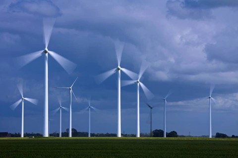 Spinning blades of wind turbines at the wind farm against stormy skies