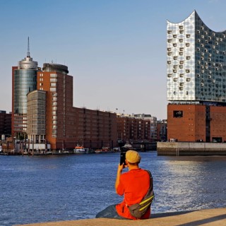 A man takes pictures of the Elbe Philharmonic Hall and Columbus House, Hafencity, Hamburg, Germany,