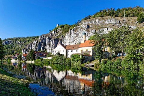 Side arm of the Altmühl, houses, Holy Spirit Parish Church, reflection in the water, on top of rock