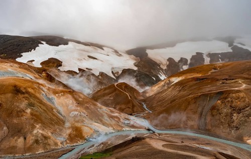 Bridge and steaming streams between colourful rhyolite mountains and snowfields, Hveradalir