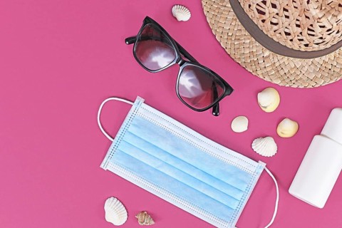 Coronavirus summer crisis concept with face mask, straw hat, sunglasses, disinfectant spray bottle