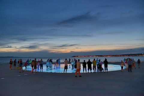 People at the Monument to the Sun, Pozdrav Suncu, by architect Nikole Bašica, at dusk, Zadar,