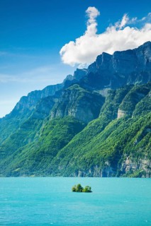 Sunny view over Lake Walen with the small chive island in the turquoise water and mountain range