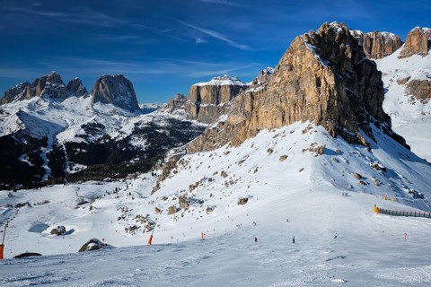 View of a ski resort piste with people skiing in Dolomites in Italy. Ski area Belvedere. Canazei,